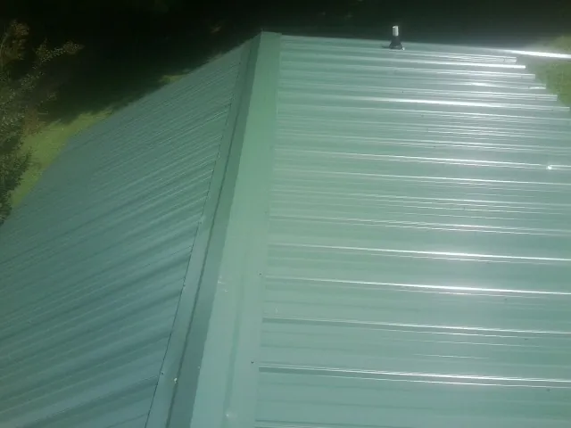 New green metal panels meeting at the ridge of a roof — Flat Roof Repair work by our crew in Grenloch