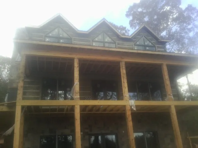 Dormers and porch framing on a large log home under construction — Roof Coating work by our crew in Grenloch
