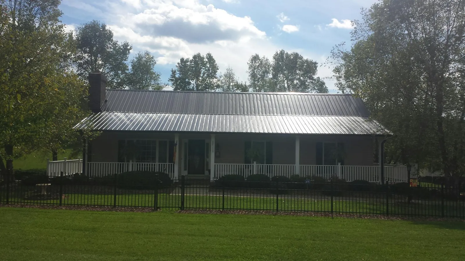 Gray metal roof on a brick ranch with a full width front porch — Gutter Guard Installation work by our crew in Grenloch
