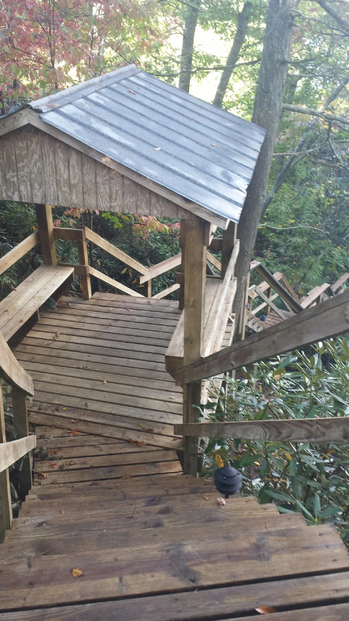 Metal roofed shelter over wooden steps on a wooded walkway — Skylight Repair & Installation work by our crew in Grenloch