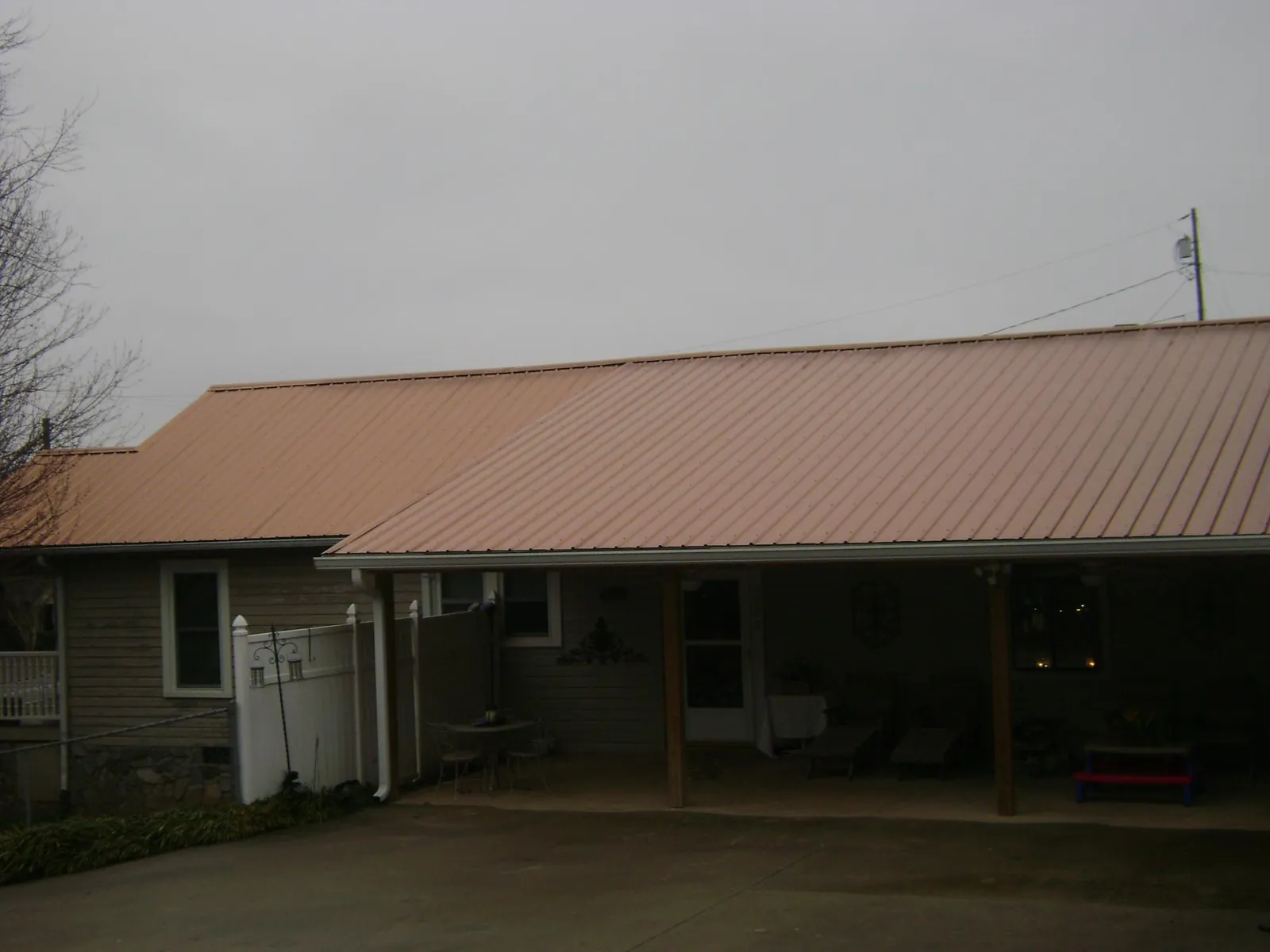 Copper toned metal roof over a wide covered patio in Grenloch