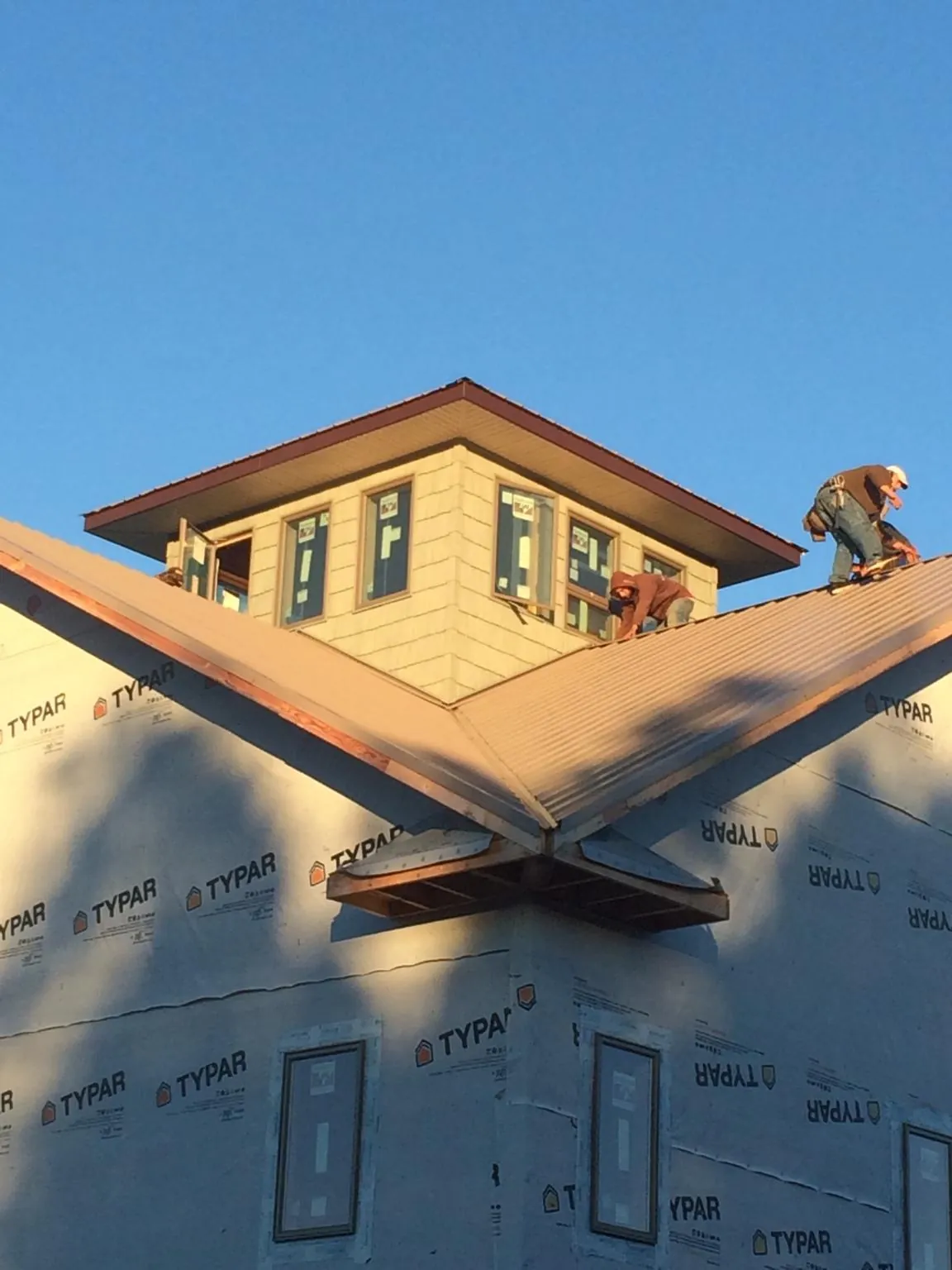 Roofers working around a rooftop cupola on a new metal roof at sunset — Roof Waterproofing in Grenloch by Roofing Brothers